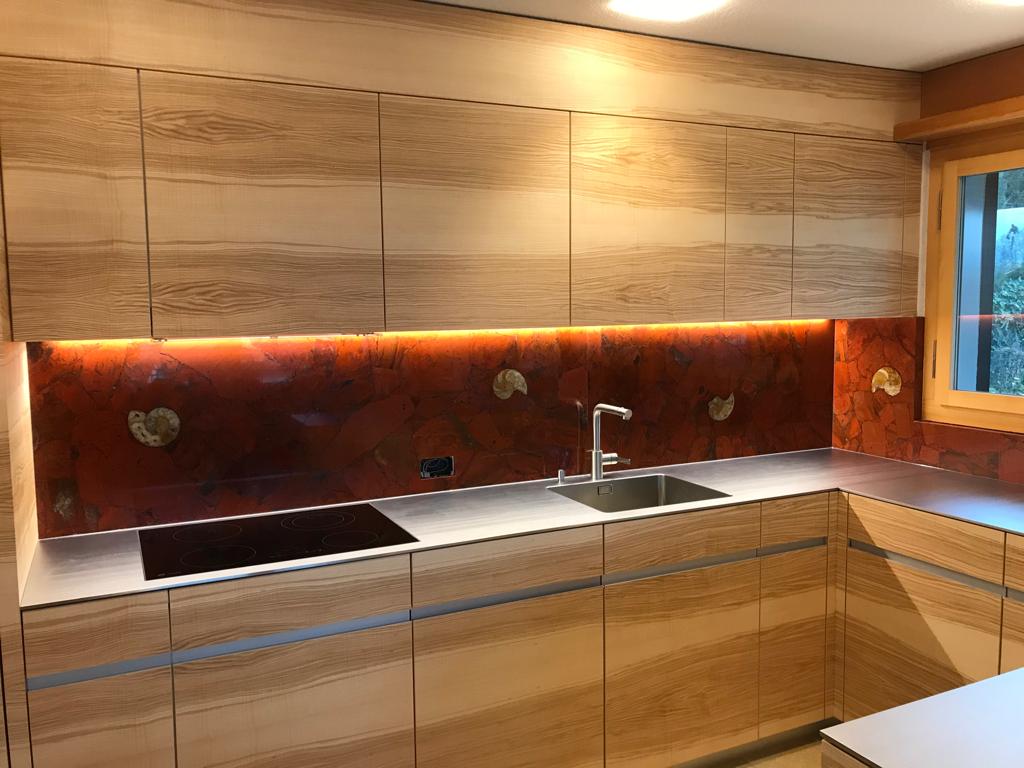 Küche mit Holzfronten und roter Onyx-Rückwand